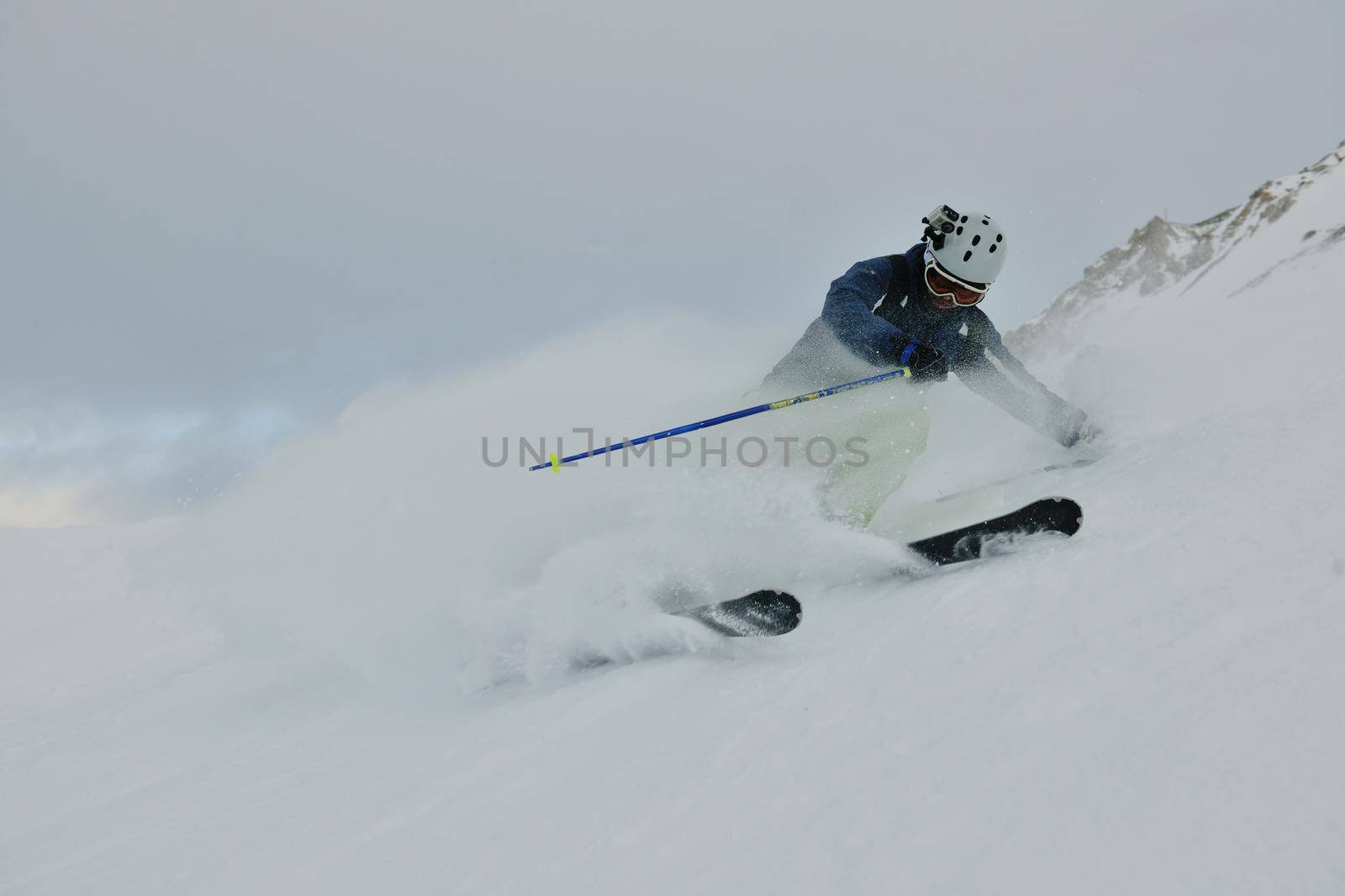 skier skiing downhill on fresh powder snow  with sun and mountains in background