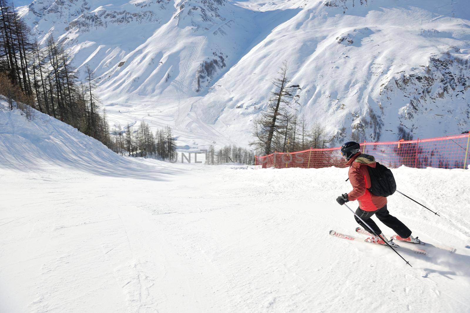 skier skiing downhill on fresh powder snow  with sun and mountains in background