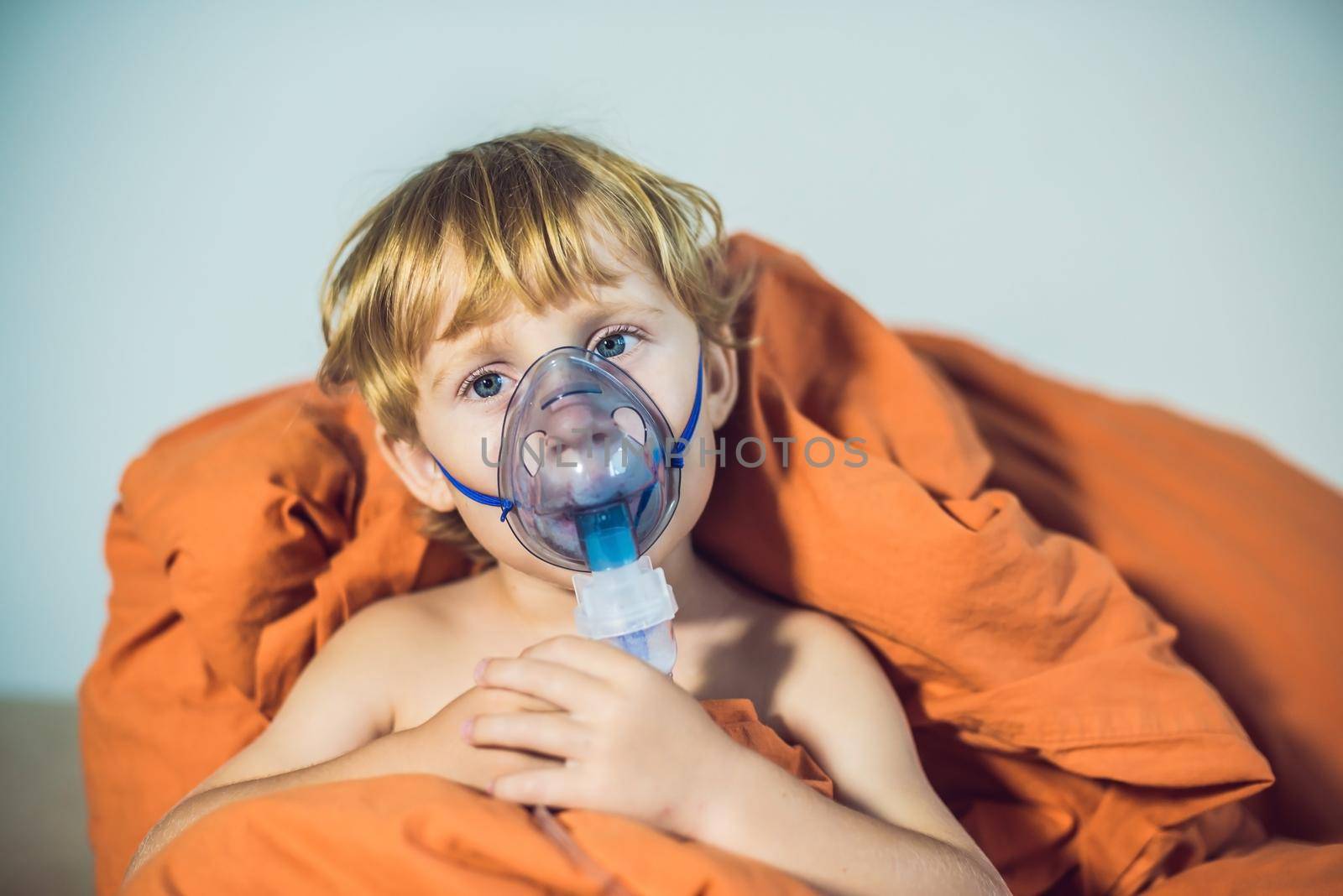 Boy making inhalation with a nebulizer at home by galitskaya