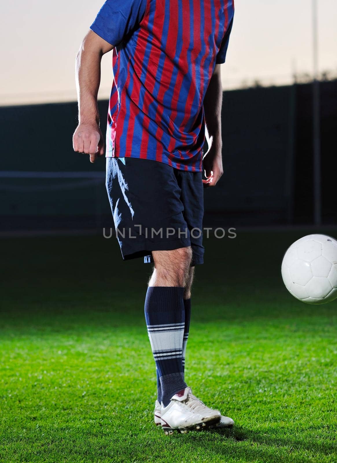 soccer player doing kick with ball on football stadium  field  isolated on black background  in night