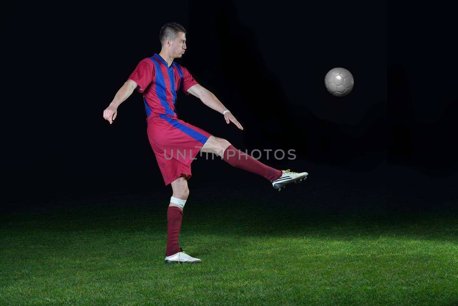 soccer player doing kick with ball on football stadium  field  isolated on black background