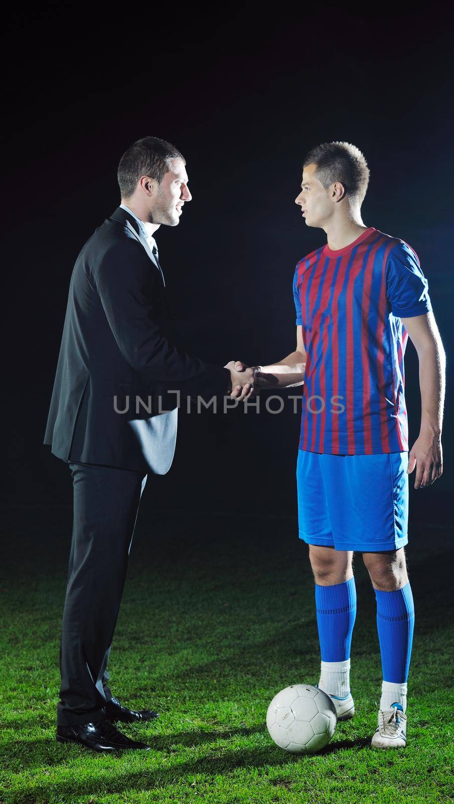 soccer  sport manager in business suit coach and football player on stadium with green grass and white ball