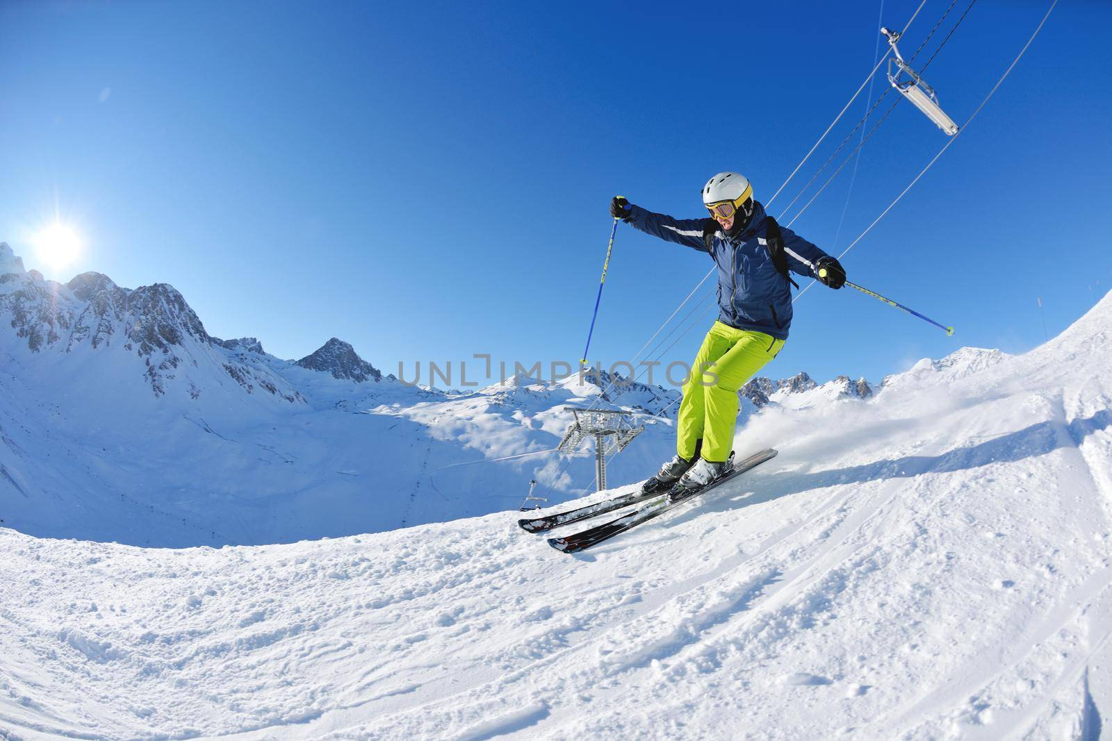 skier skiing downhill on fresh powder snow  with sun and mountains in background