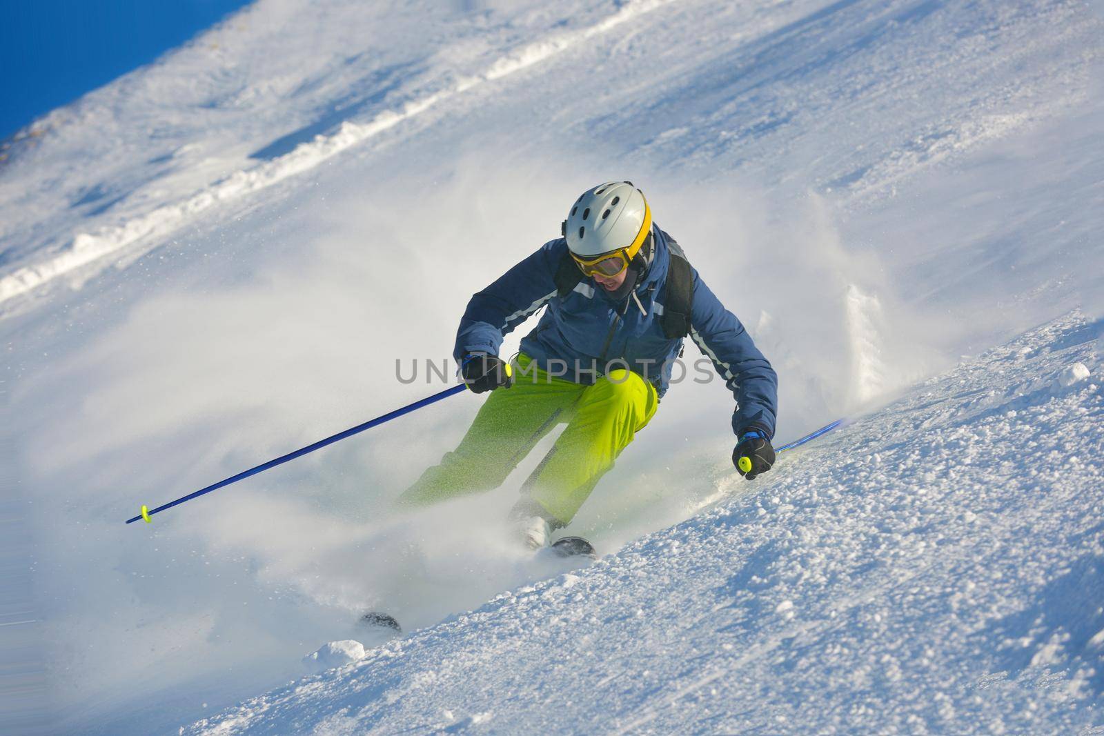 skier skiing downhill on fresh powder snow  with sun and mountains in background