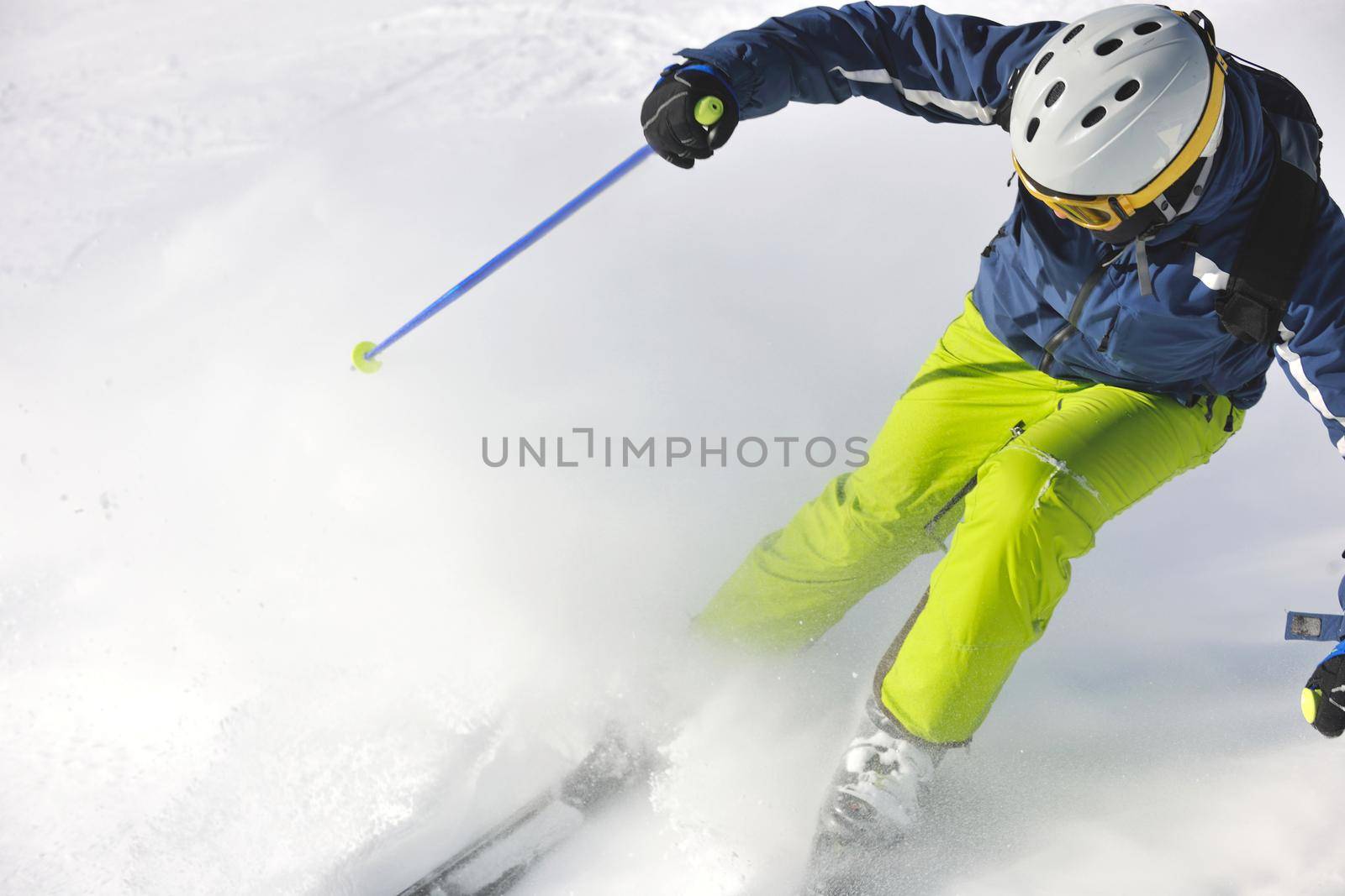 skier skiing downhill on fresh powder snow  with sun and mountains in background