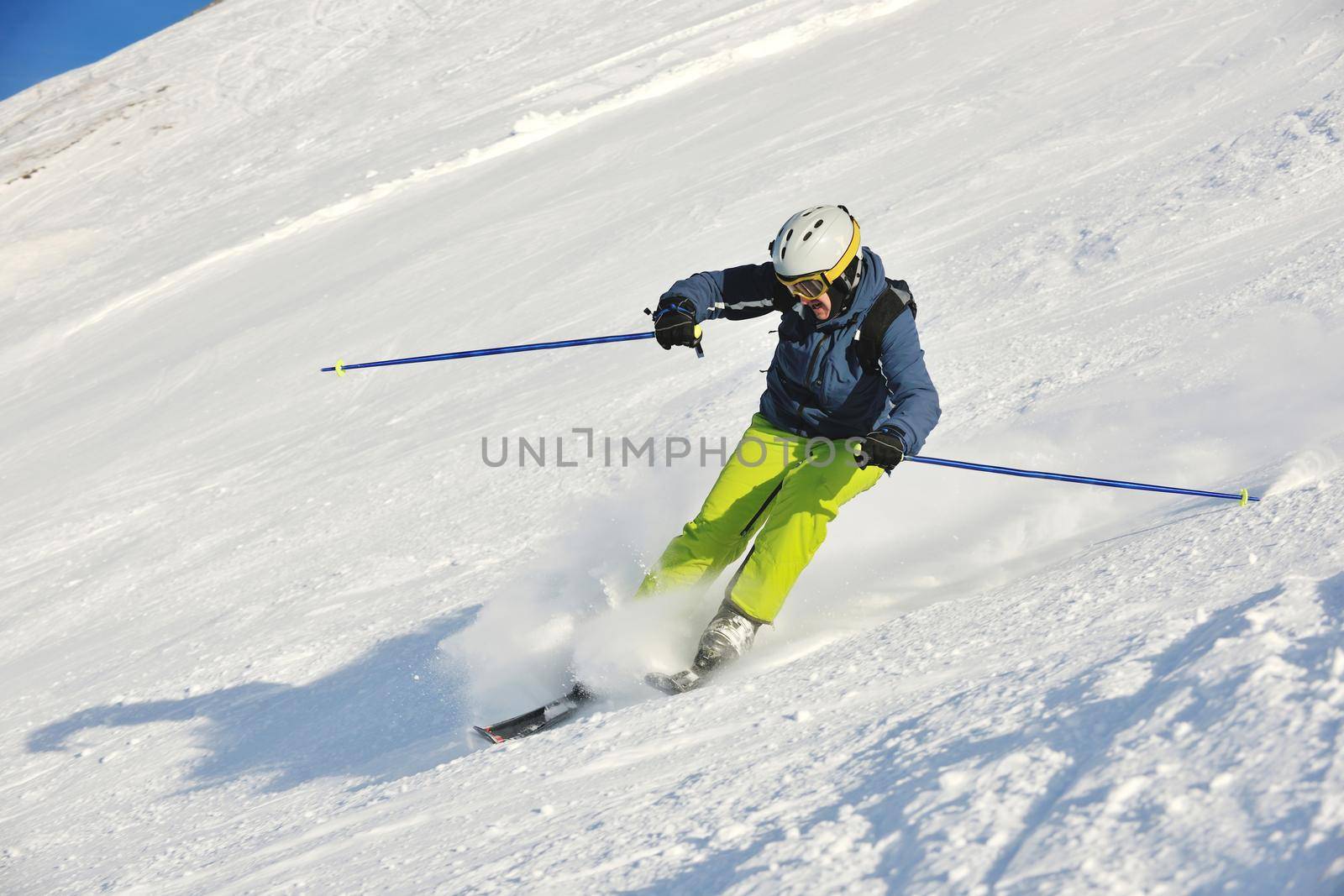 skier skiing downhill on fresh powder snow  with sun and mountains in background