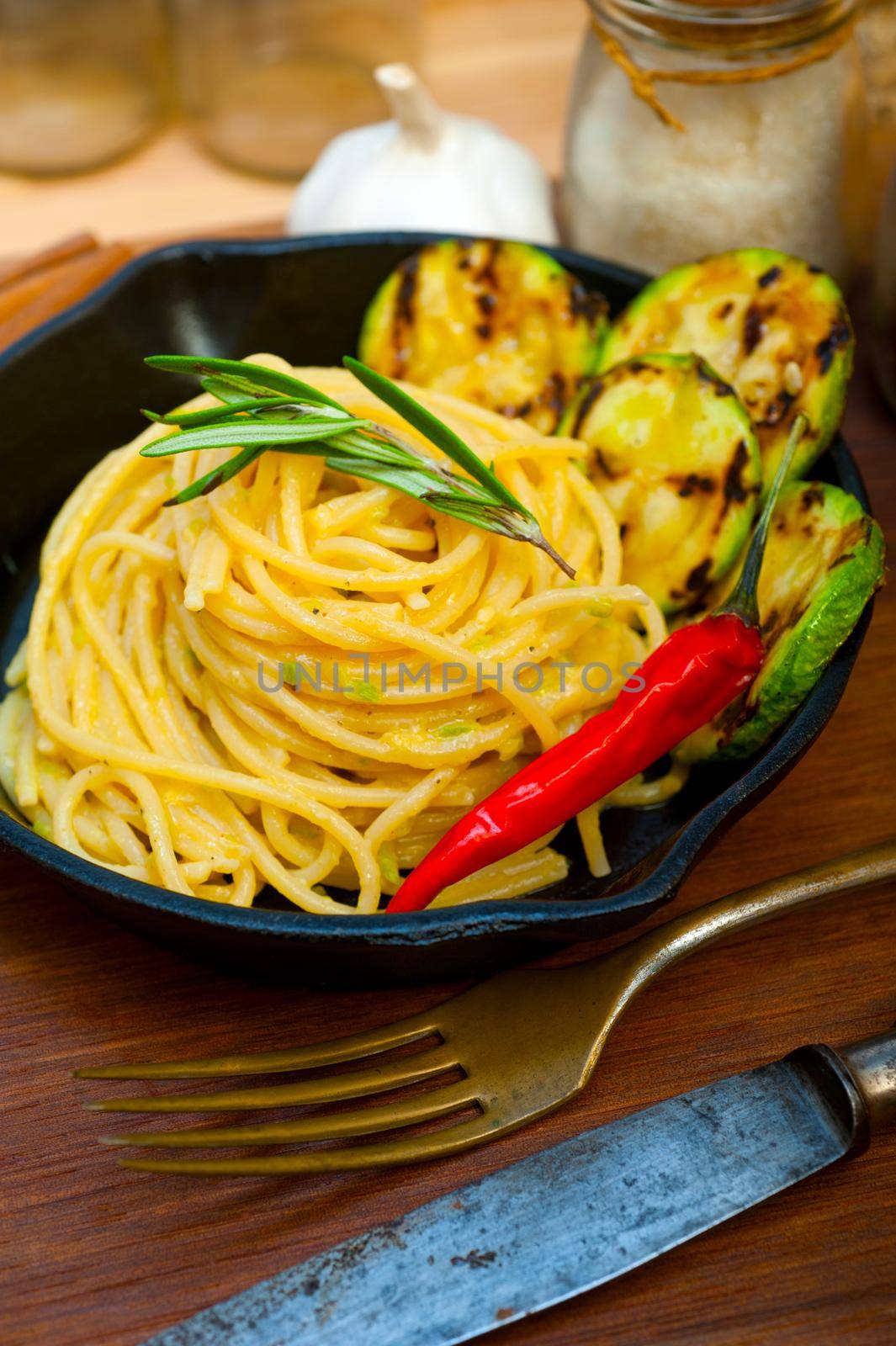 italian spaghetti pasta with zucchini sauce on iron skillet by keko64