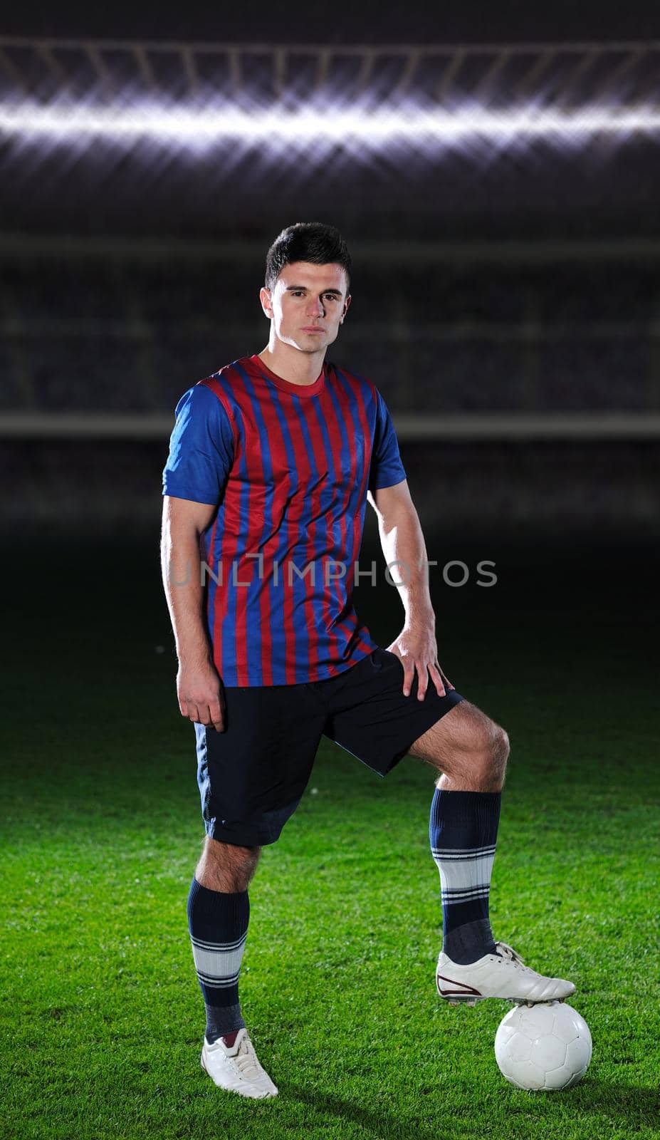 portrait of young handsome soccer player man at football stadium and green grass