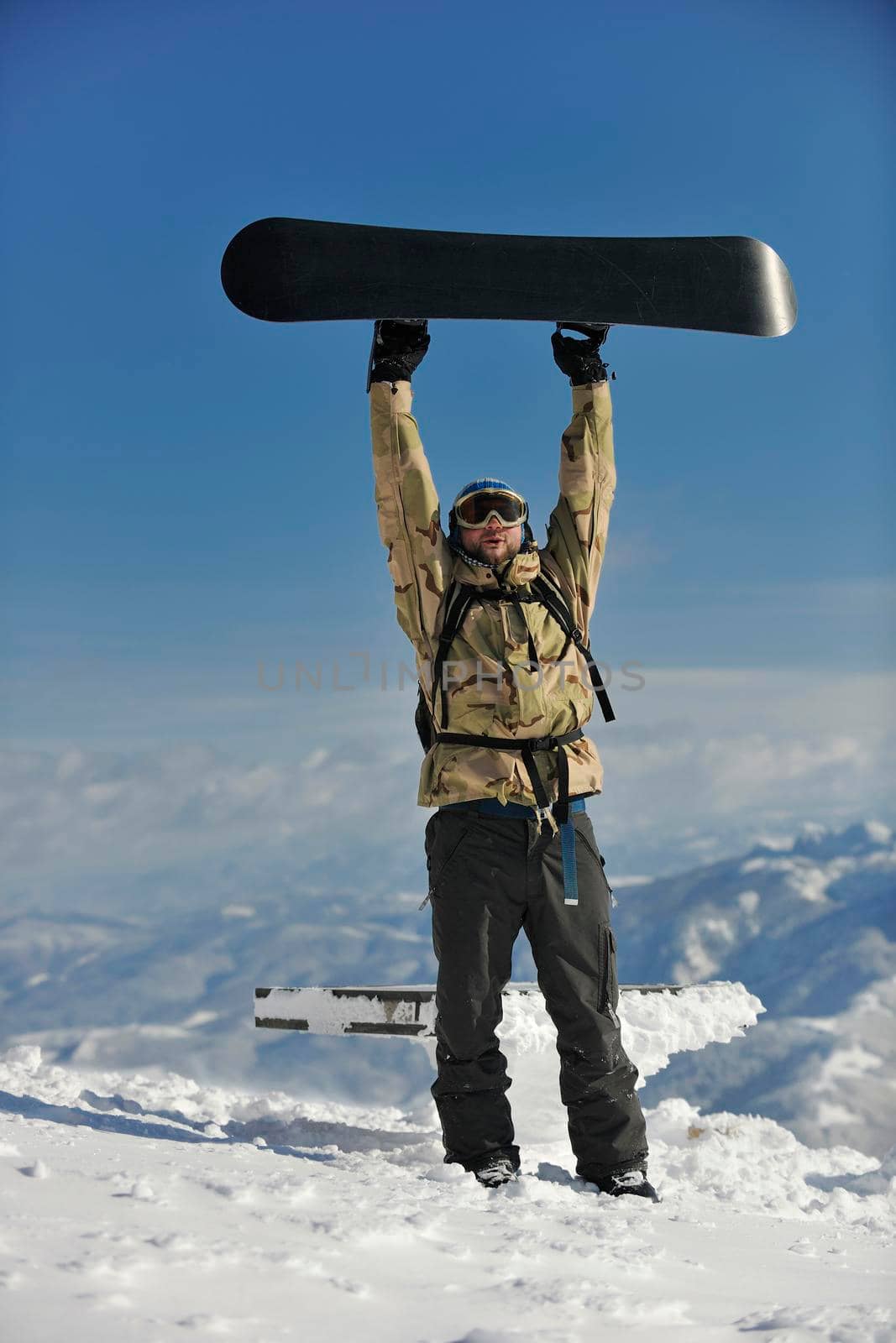 snowboarder relaxing and posing at sunny day on winter season with blue sky in background