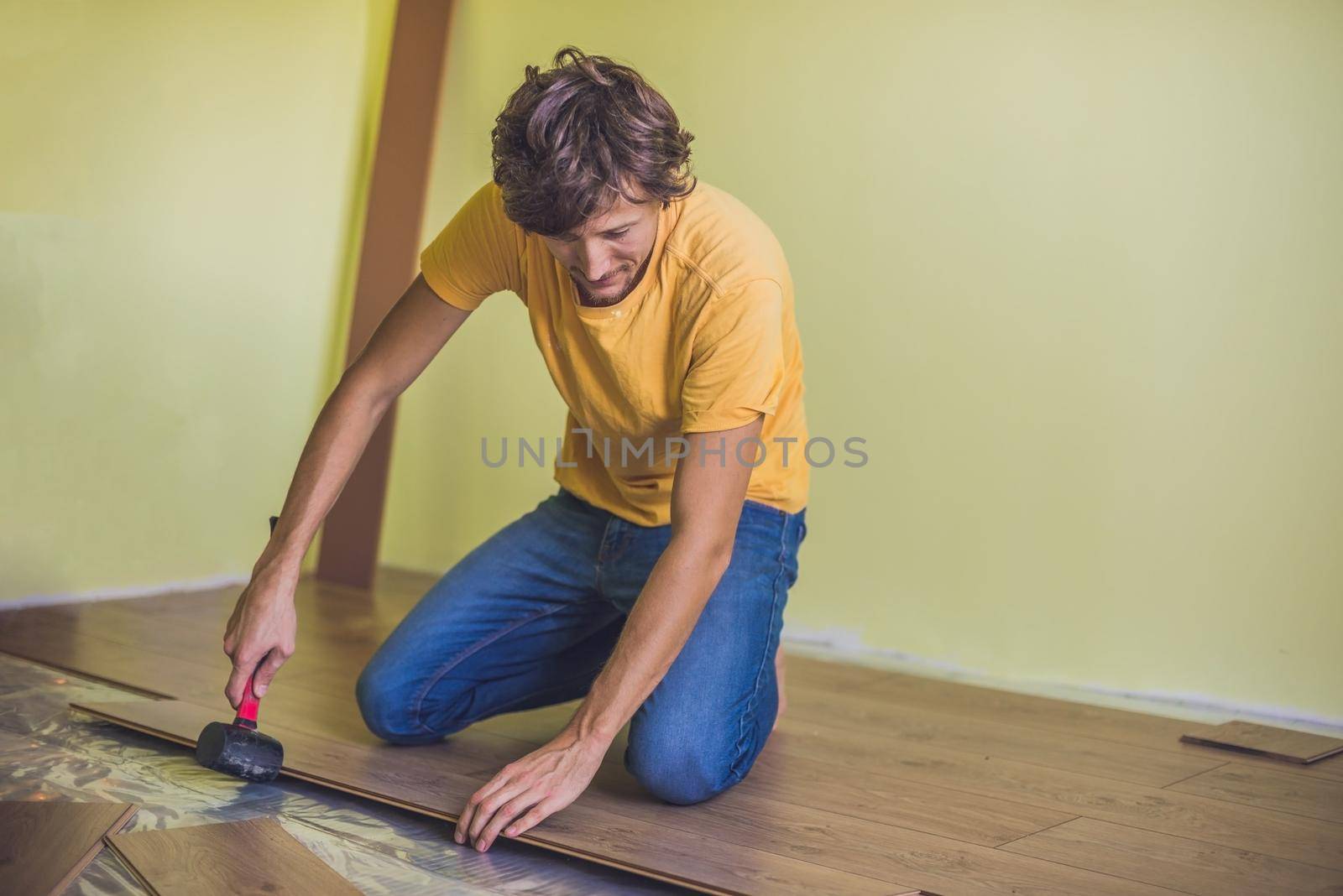 Man installing new wooden laminate flooring. infrared floor heating system under laminate floor by galitskaya