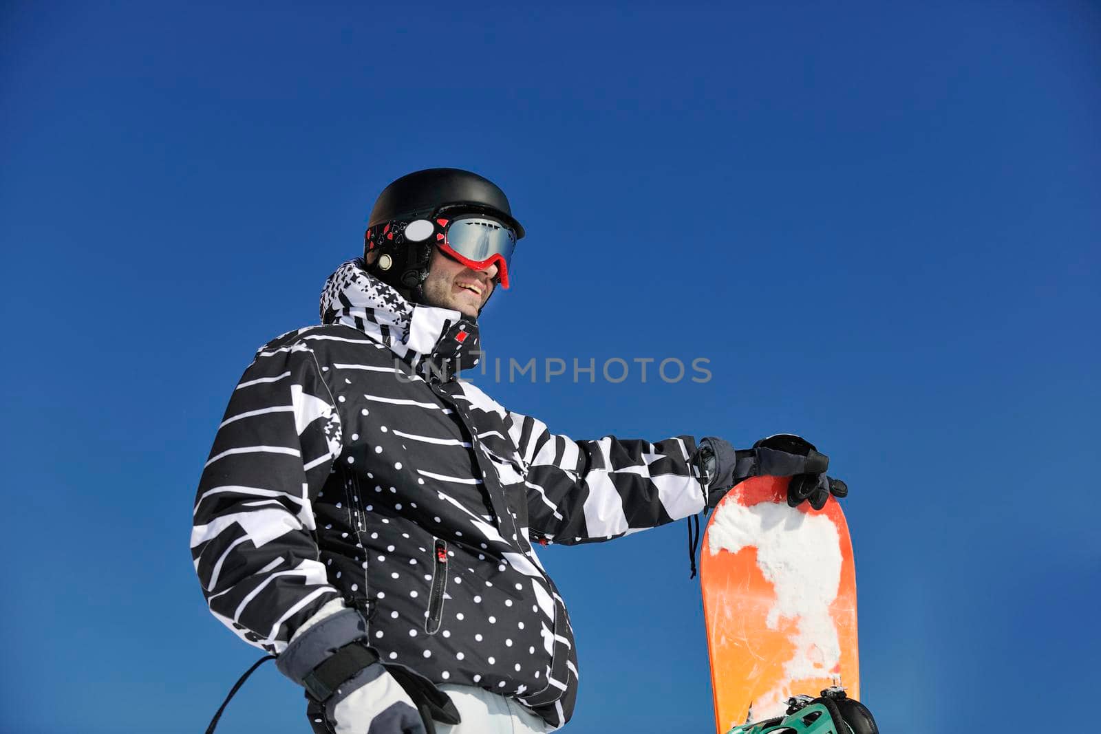 snowboarder relaxing and posing at sunny day on winter season with blue sky in background