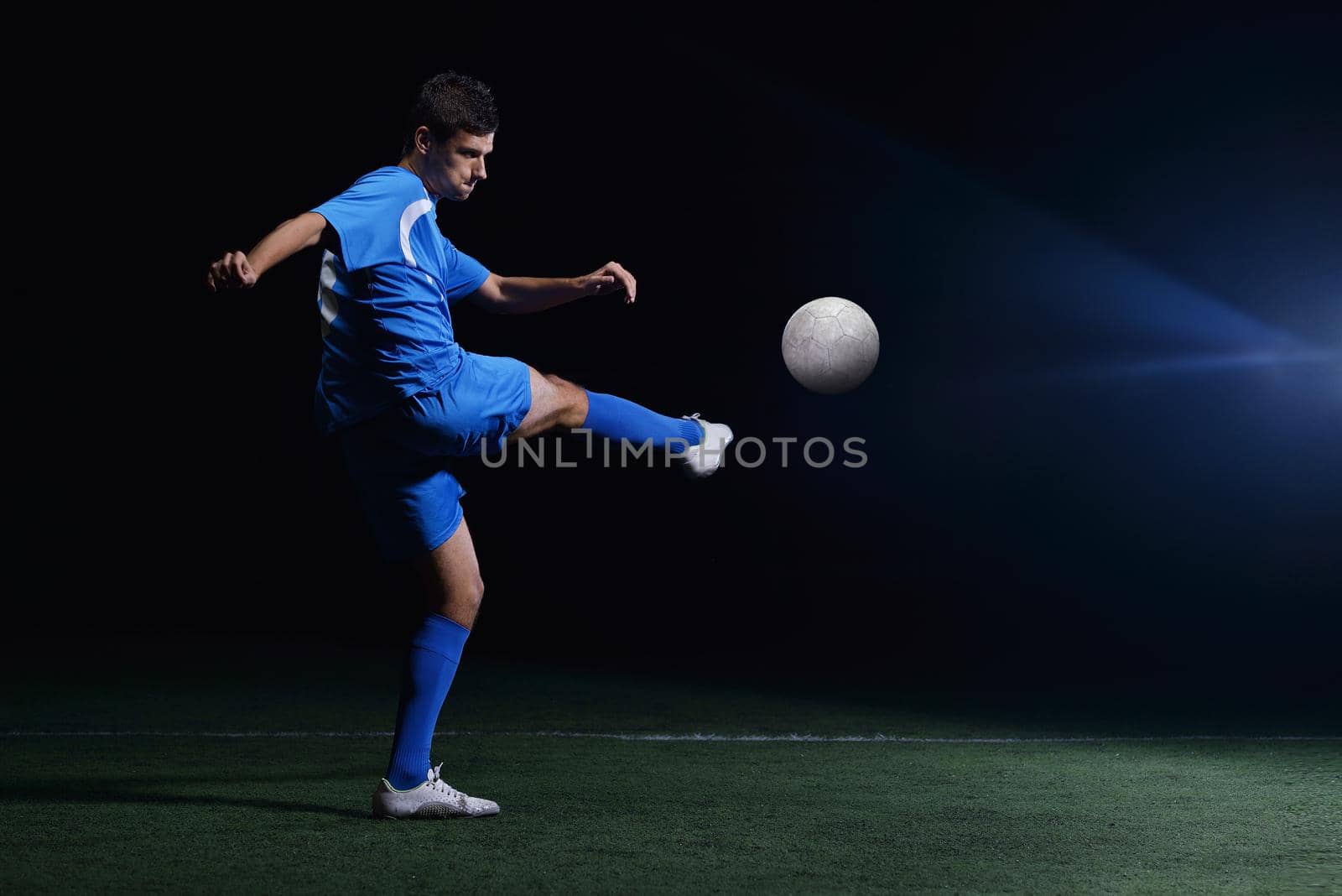 soccer player doing kick with ball on football stadium  field  isolated on black background