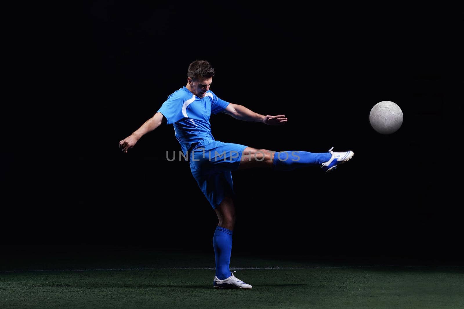 soccer player doing kick with ball on football stadium  field  isolated on black background