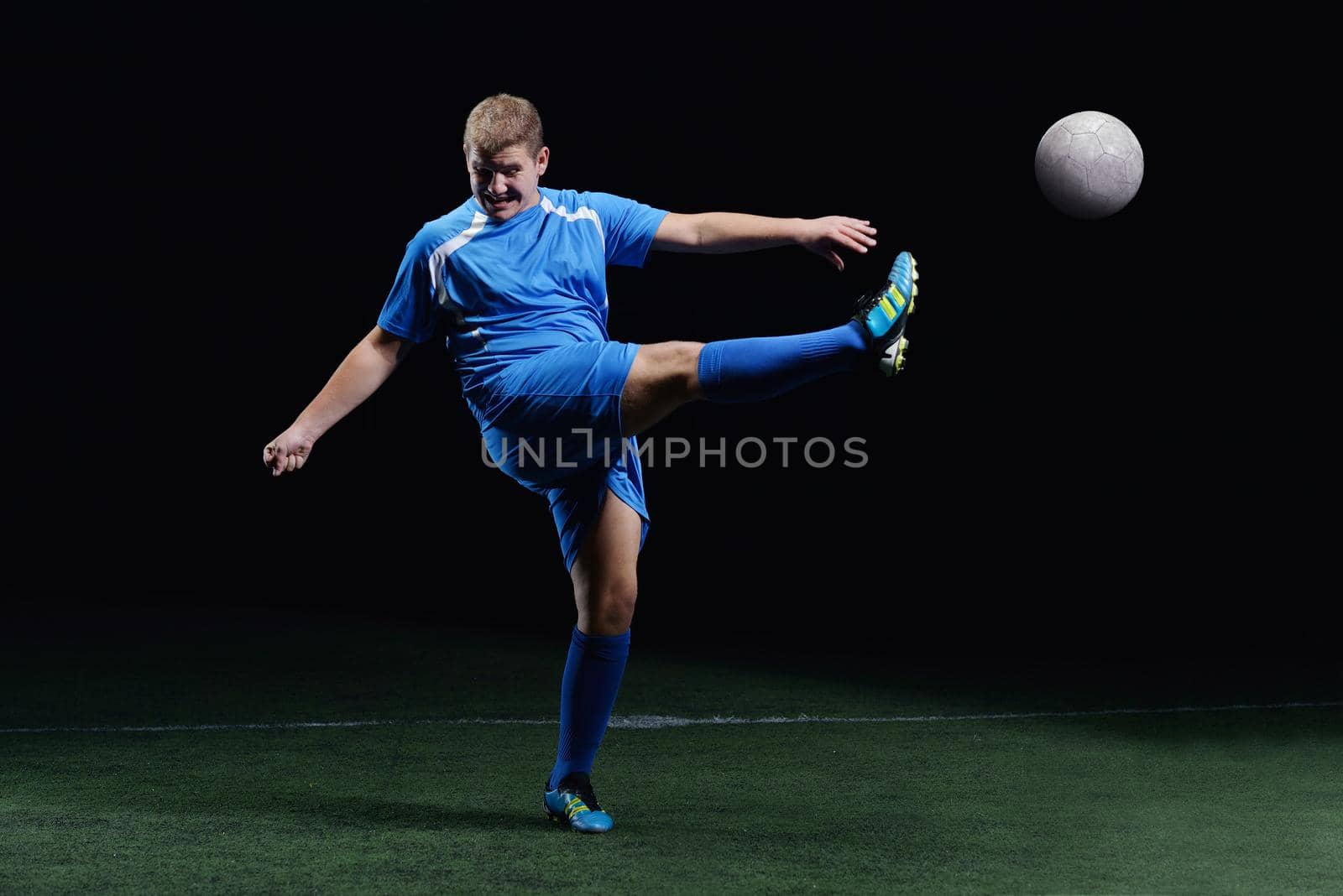 soccer player doing kick with ball on football stadium  field  isolated on black background