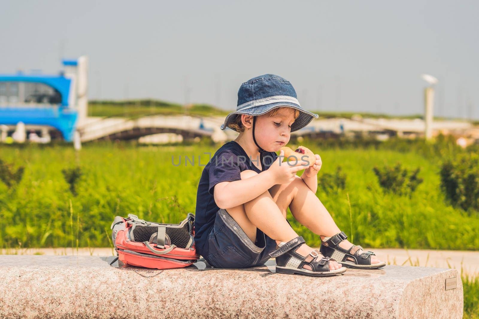 A boy eats his snack on a park bench by galitskaya