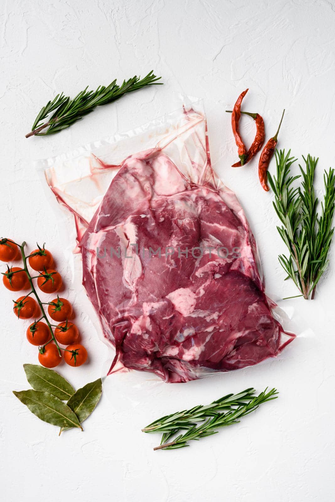 Piece of raw lamb meat set, with ingredients and herbs, on white stone table background, top view flat lay