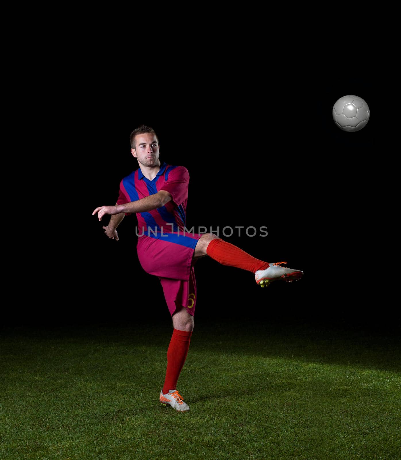 soccer player doing kick with ball on football stadium  field  isolated on black background