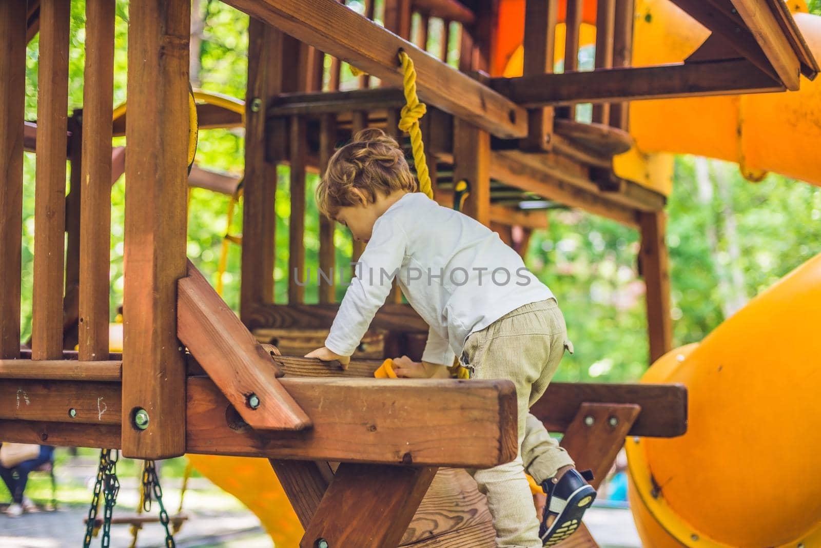 Cute little boy is playing on a wooden playground.