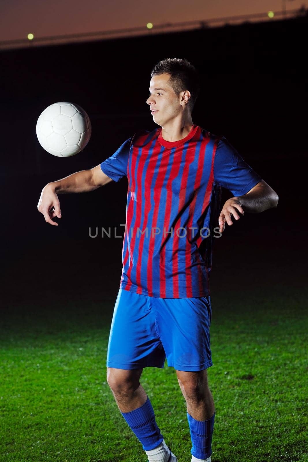 soccer player doing kick with ball on football stadium  field  isolated on black background  in night