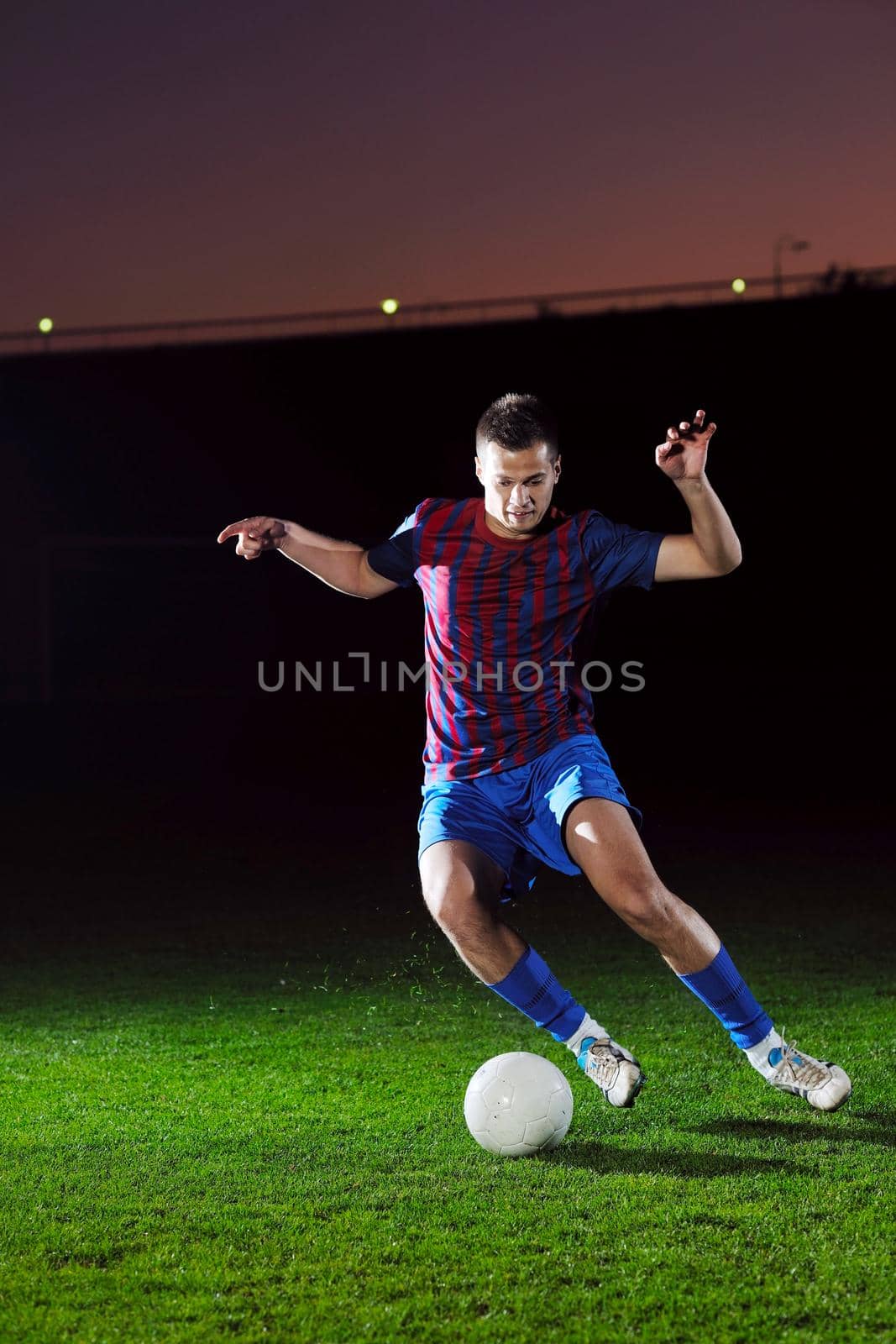 soccer player doing kick with ball on football stadium  field  isolated on black background  in night