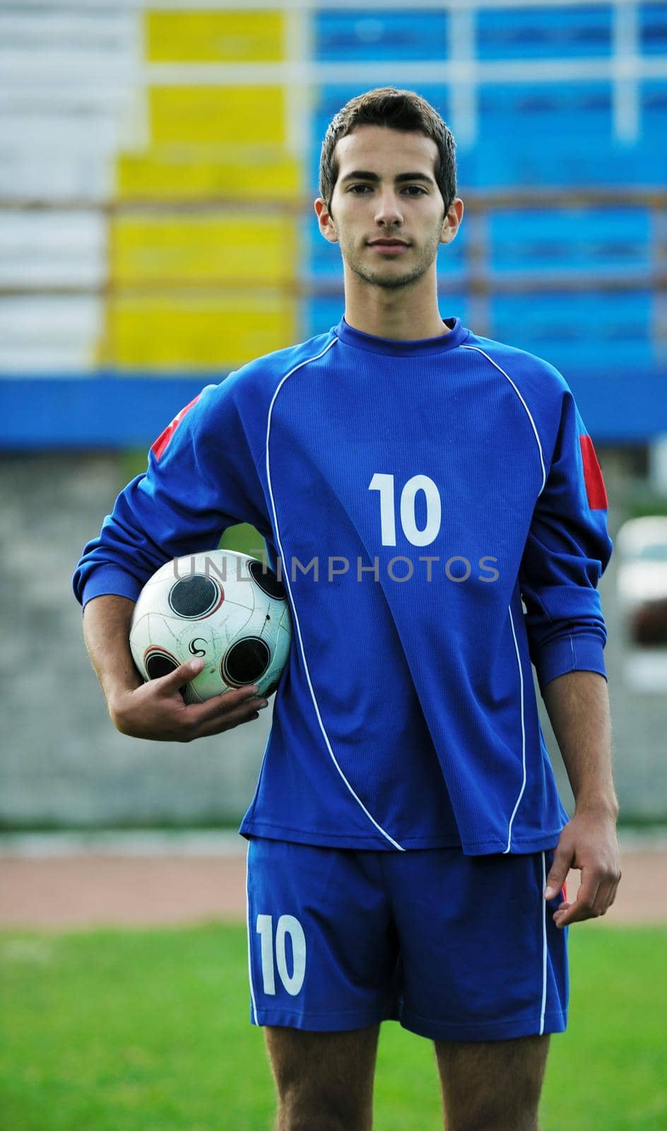 portrait of young handsome soccer player man at football stadium and green grass