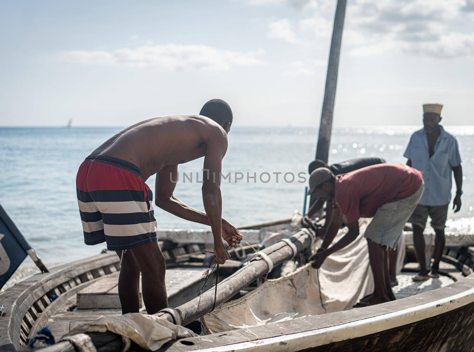 African men working on boat with sail by Zurijeta