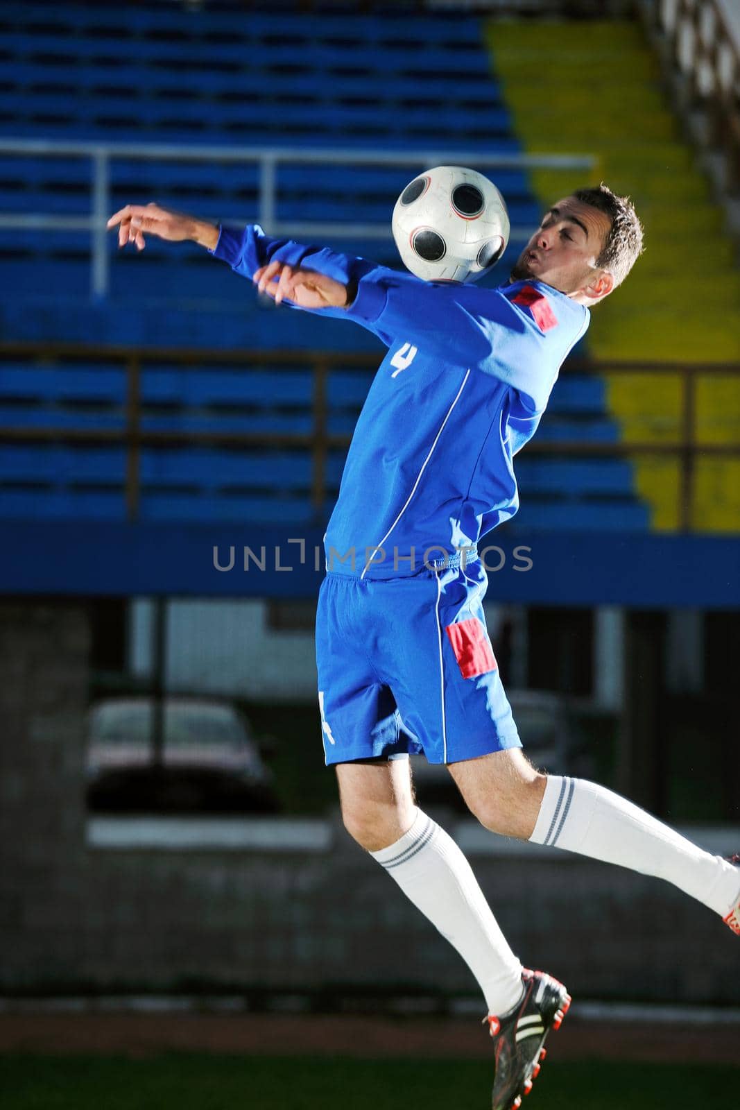 soccer player doing kick with ball on football stadium  field  isolated on black background  in night