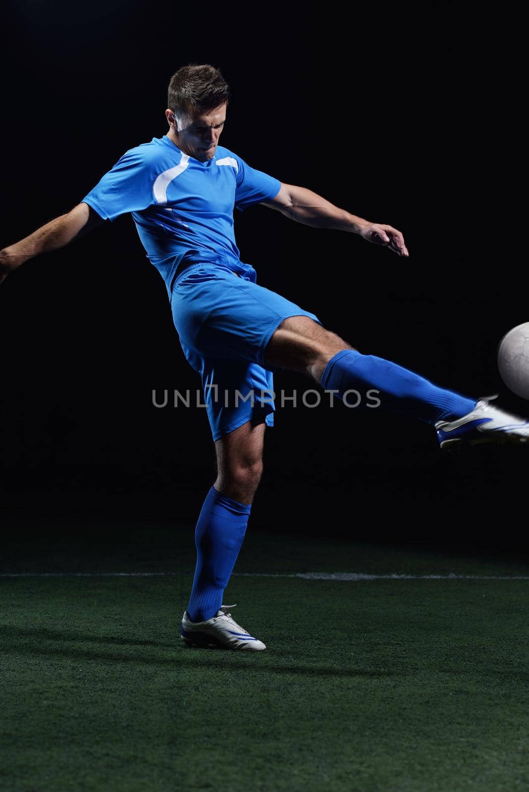 soccer player doing kick with ball on football stadium  field  isolated on black background