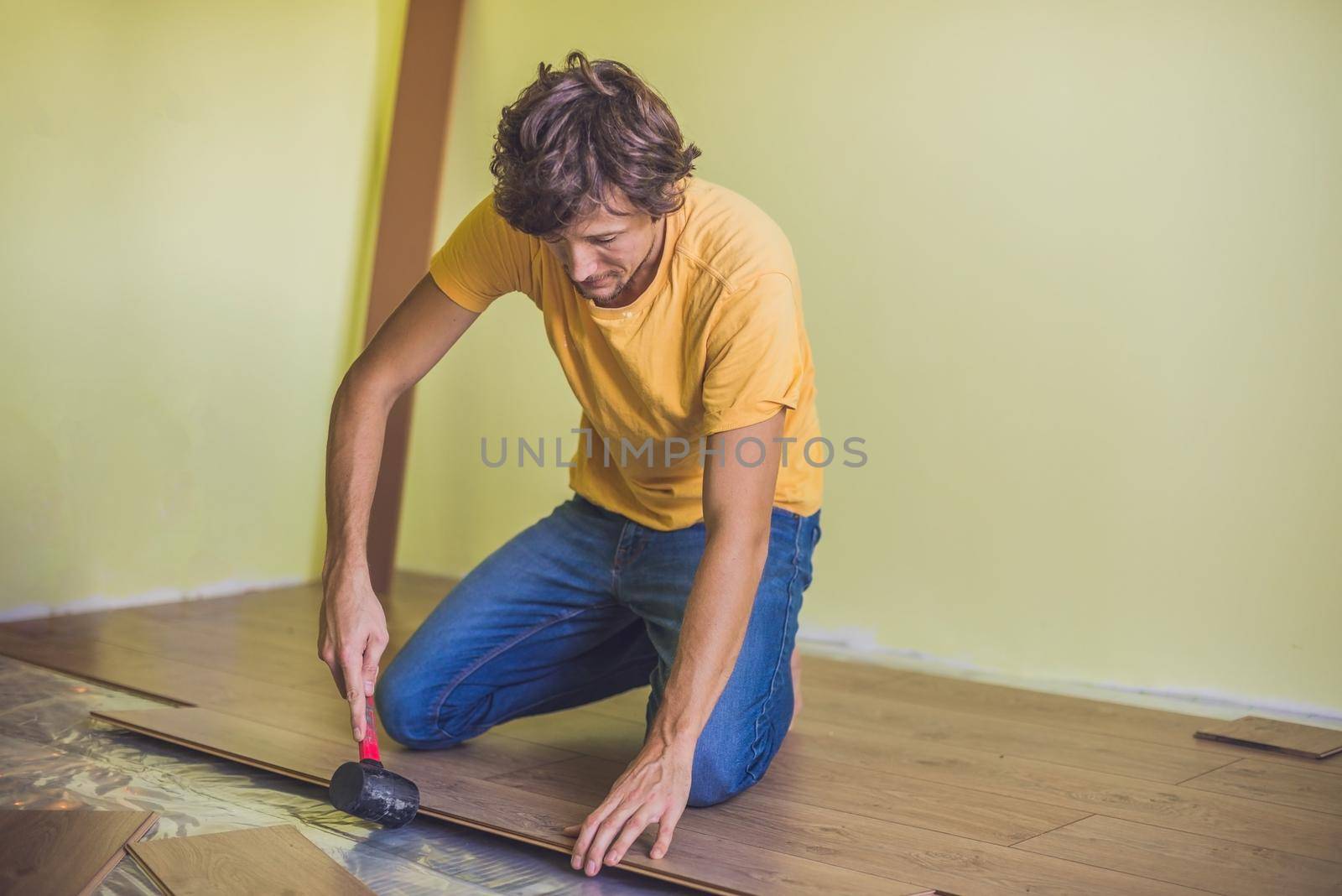 Man installing new wooden laminate flooring on a warm film floor. infrared floor heating system under laminate floor