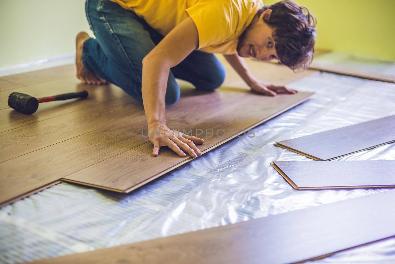 Man installing new wooden laminate flooring on a warm film floor. infrared floor heating system under laminate floor