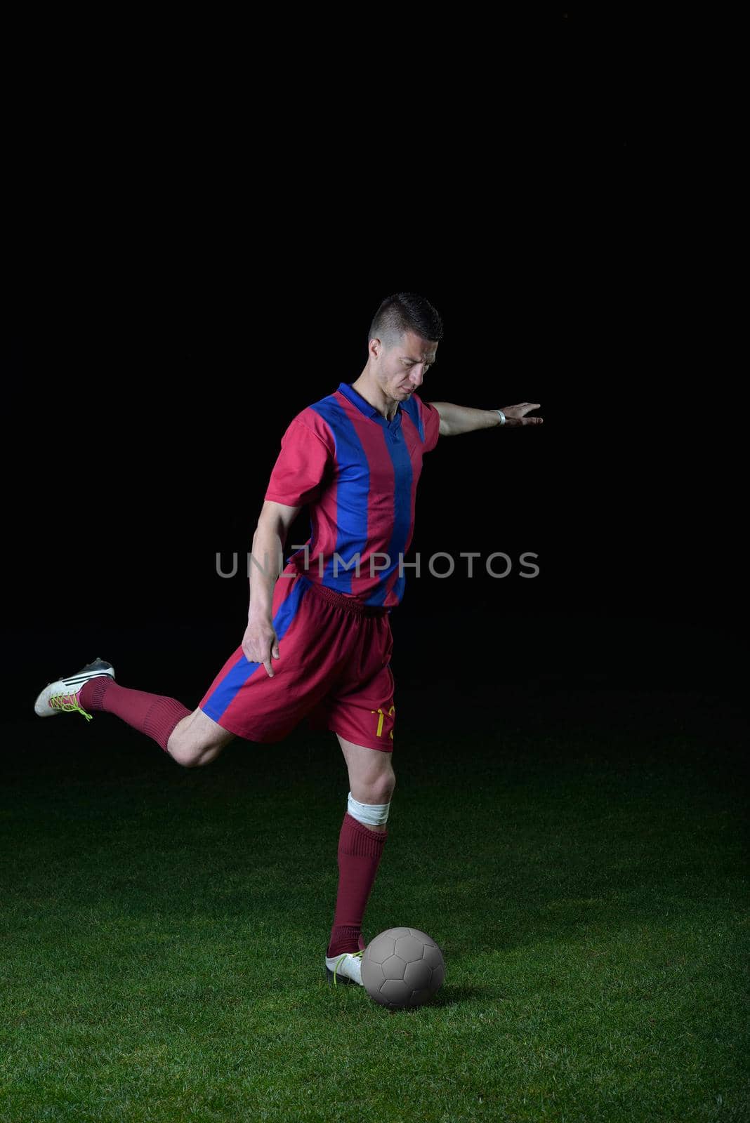 soccer player doing kick with ball on football stadium  field  isolated on black background