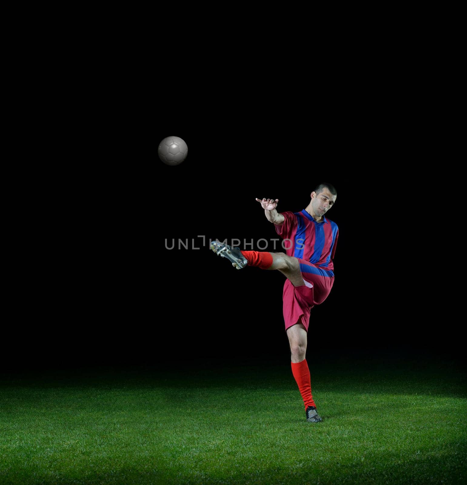 soccer player doing kick with ball on football stadium  field  isolated on black background