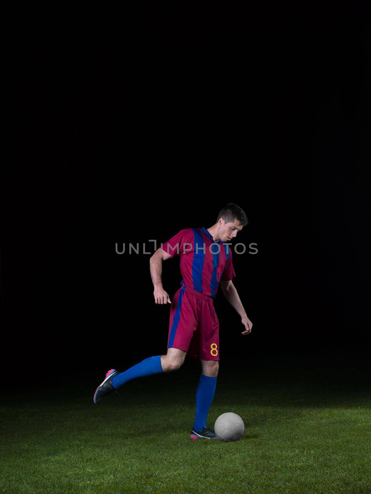 soccer player doing kick with ball on football stadium  field  isolated on black background