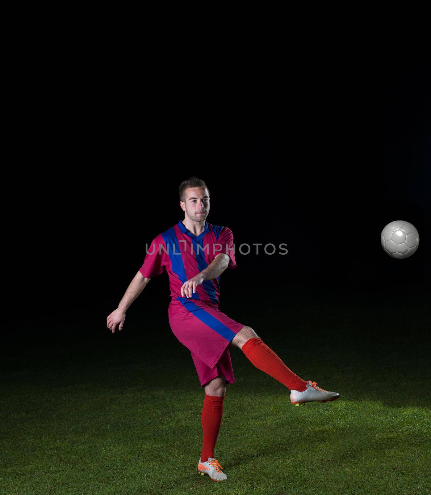 soccer player doing kick with ball on football stadium  field  isolated on black background