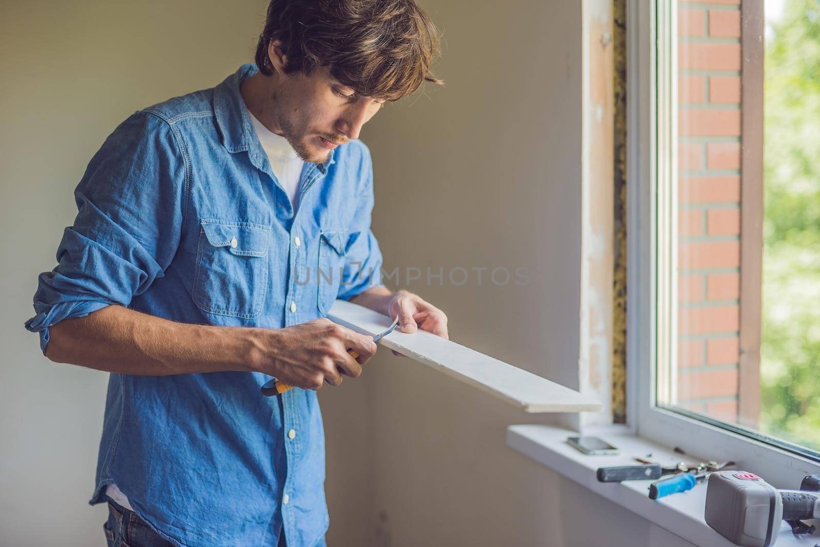 Man in a blue shirt does window installation.