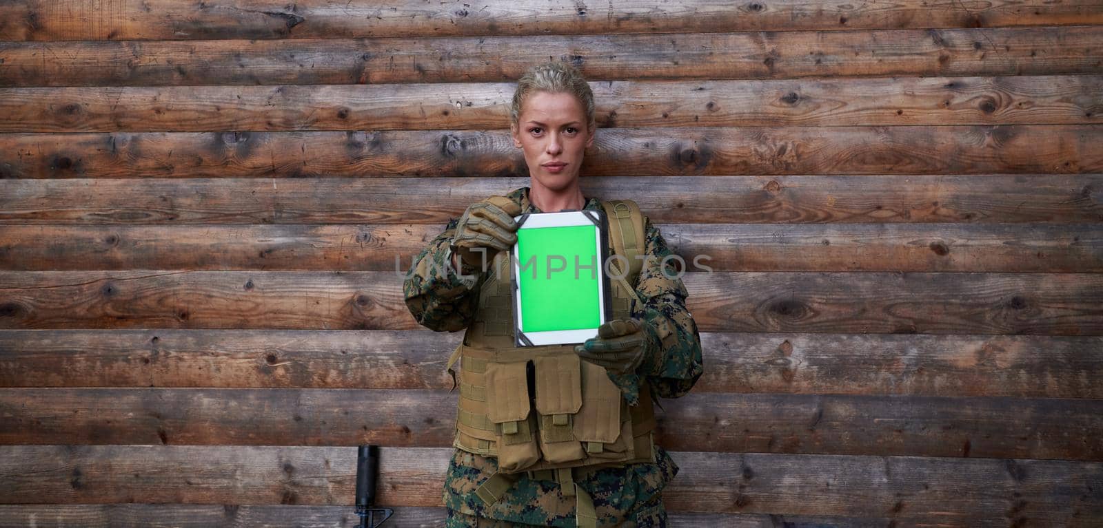 woman soldier using tablet computer  against old wooden  wall in camp