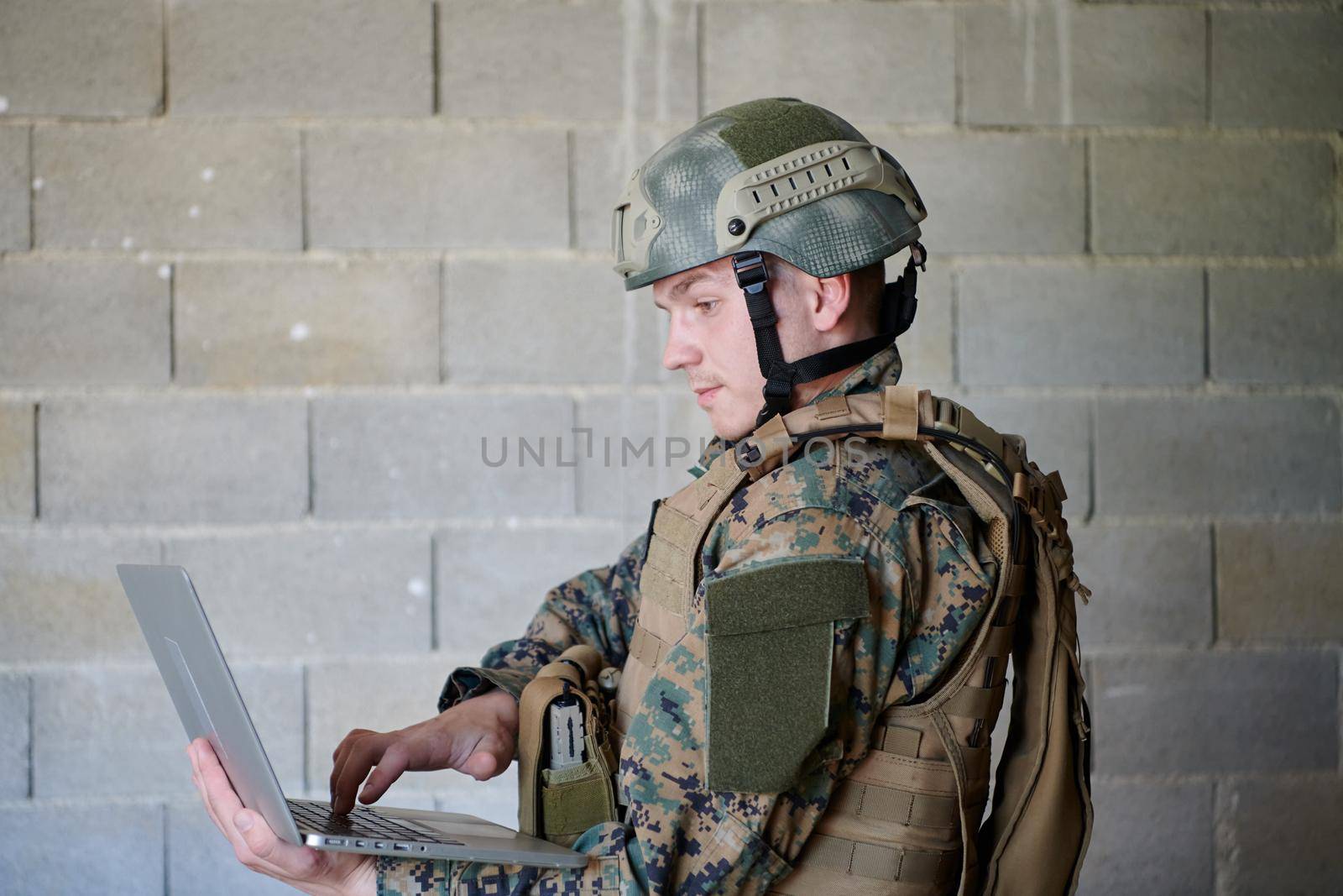 American soldier in military uniform using laptop computer for drone controlling and to stay in contact with friends and family