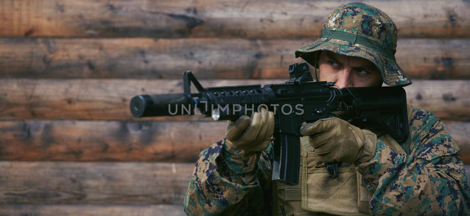 modern warfare soldier in action aiming at weapon  laser sight optics  in combat position while searching for a target in battle