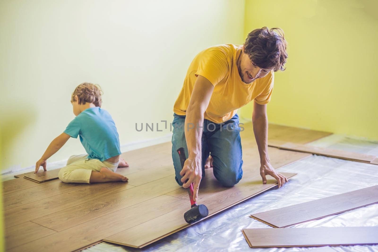 Father and son installing new wooden laminate flooring. infrared floor heating system under laminate floor by galitskaya