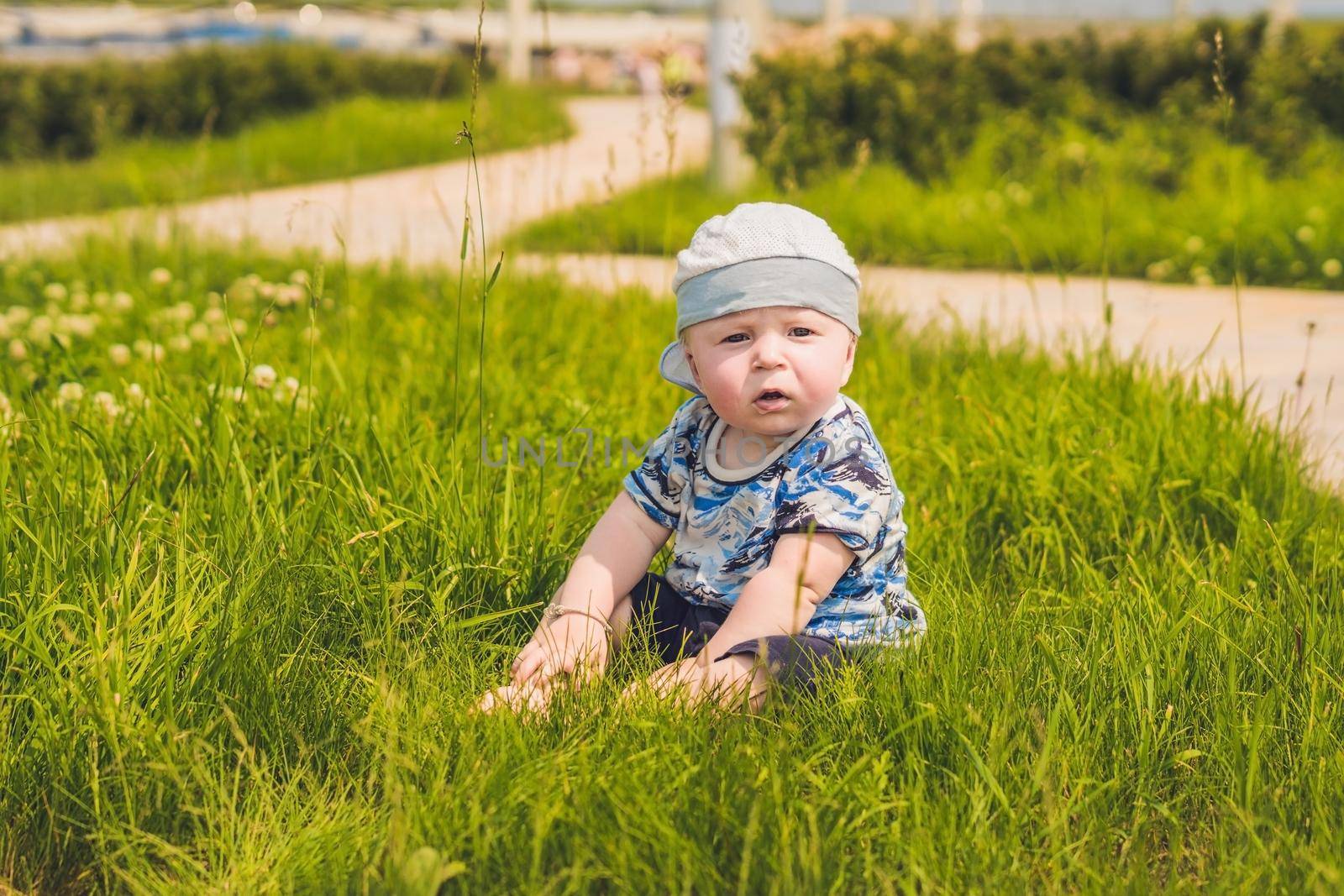 Cute little toddler baby boy child playing in the park on grass at day time. He having fun on the garden.