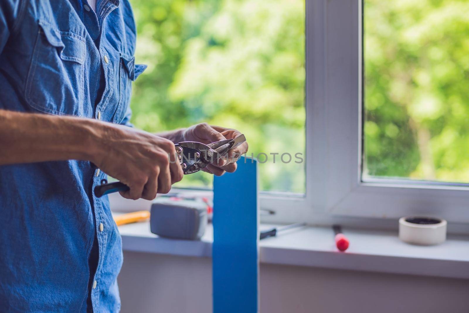 Man in a blue shirt does window installation.