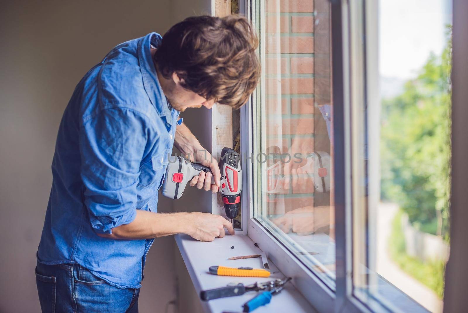 Man in a blue shirt does window installation by galitskaya