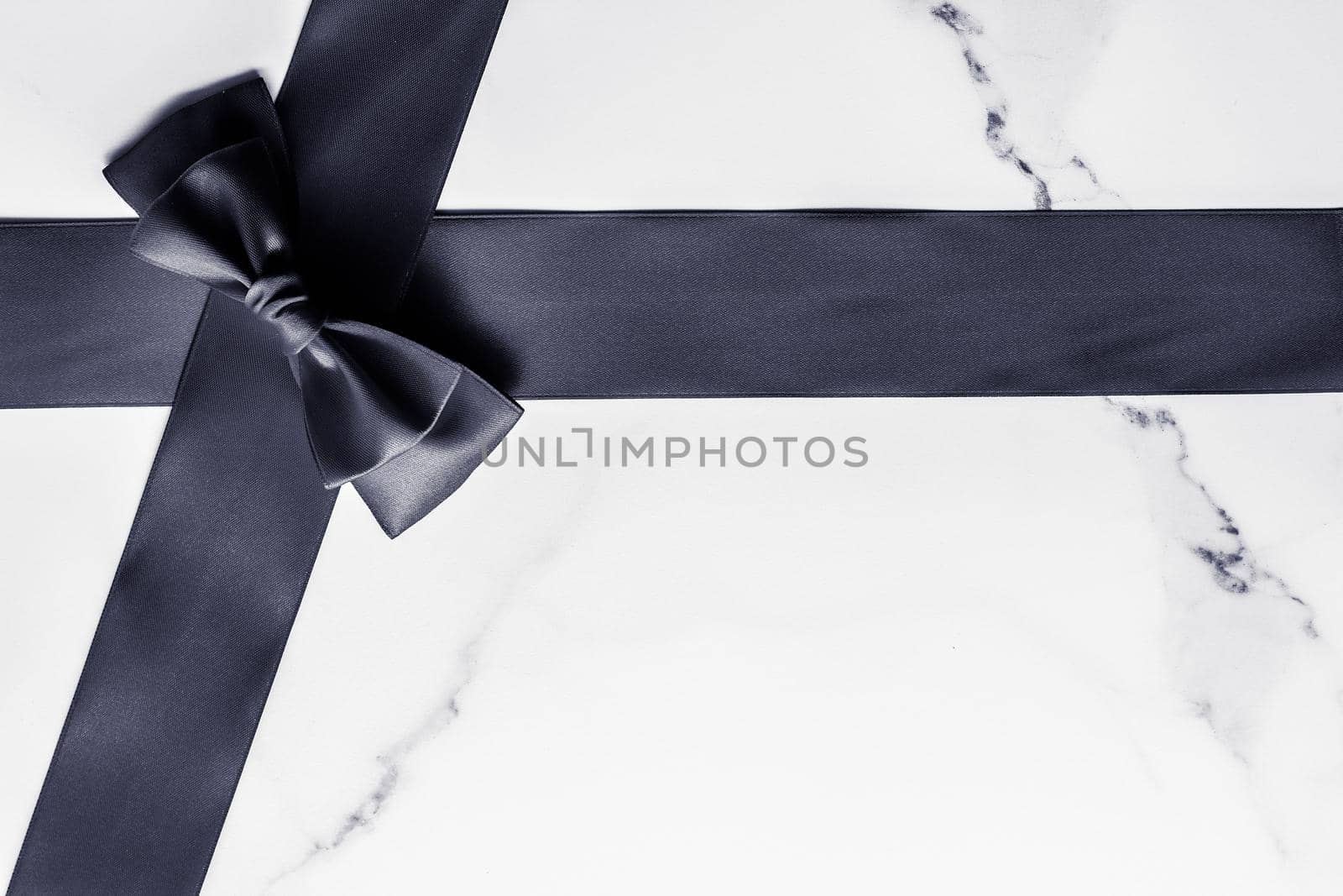 Holiday gift, decoration and sale promotion concept - Black silk ribbon and bow on marble background, flatlay