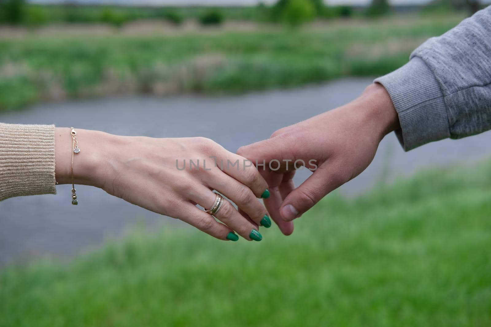 Hands of man and woman reaching to each other. Soft, gentle touch of hands on background of nature. Be hand in hand. Concept of Love, connection, help, relation, community, togetherness, symbolism by oliavesna