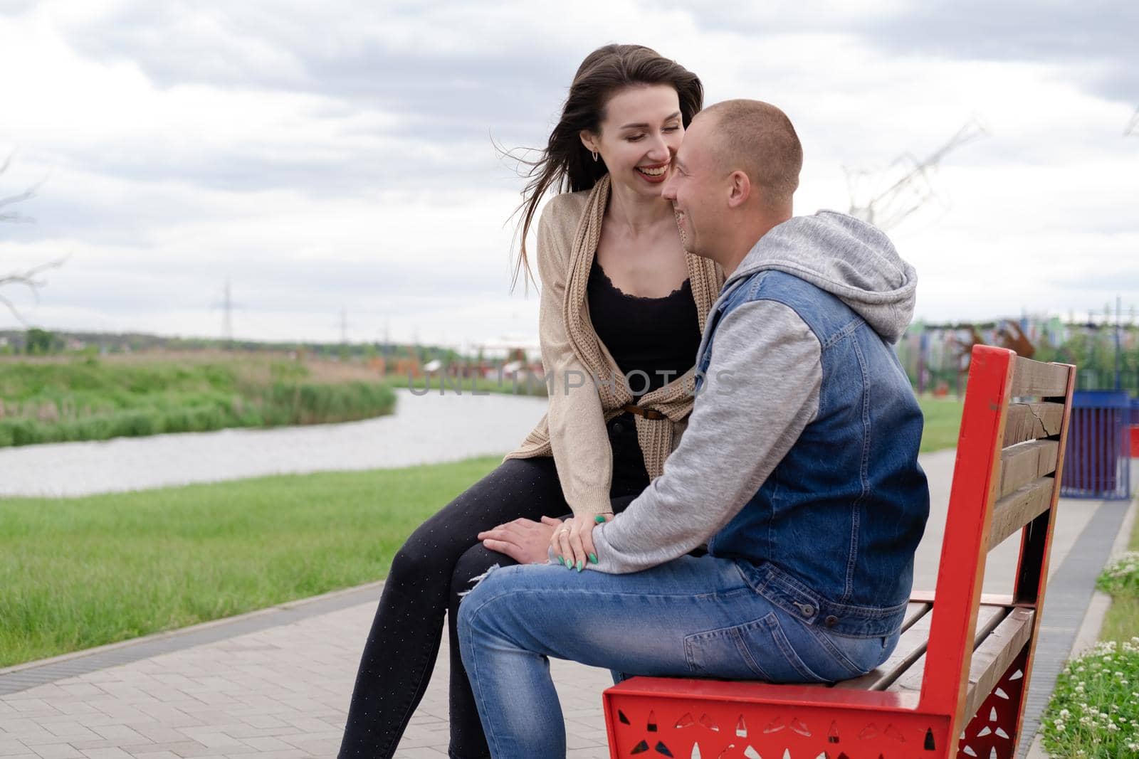 beautiful young couple sitting on a bench in the park by oliavesna