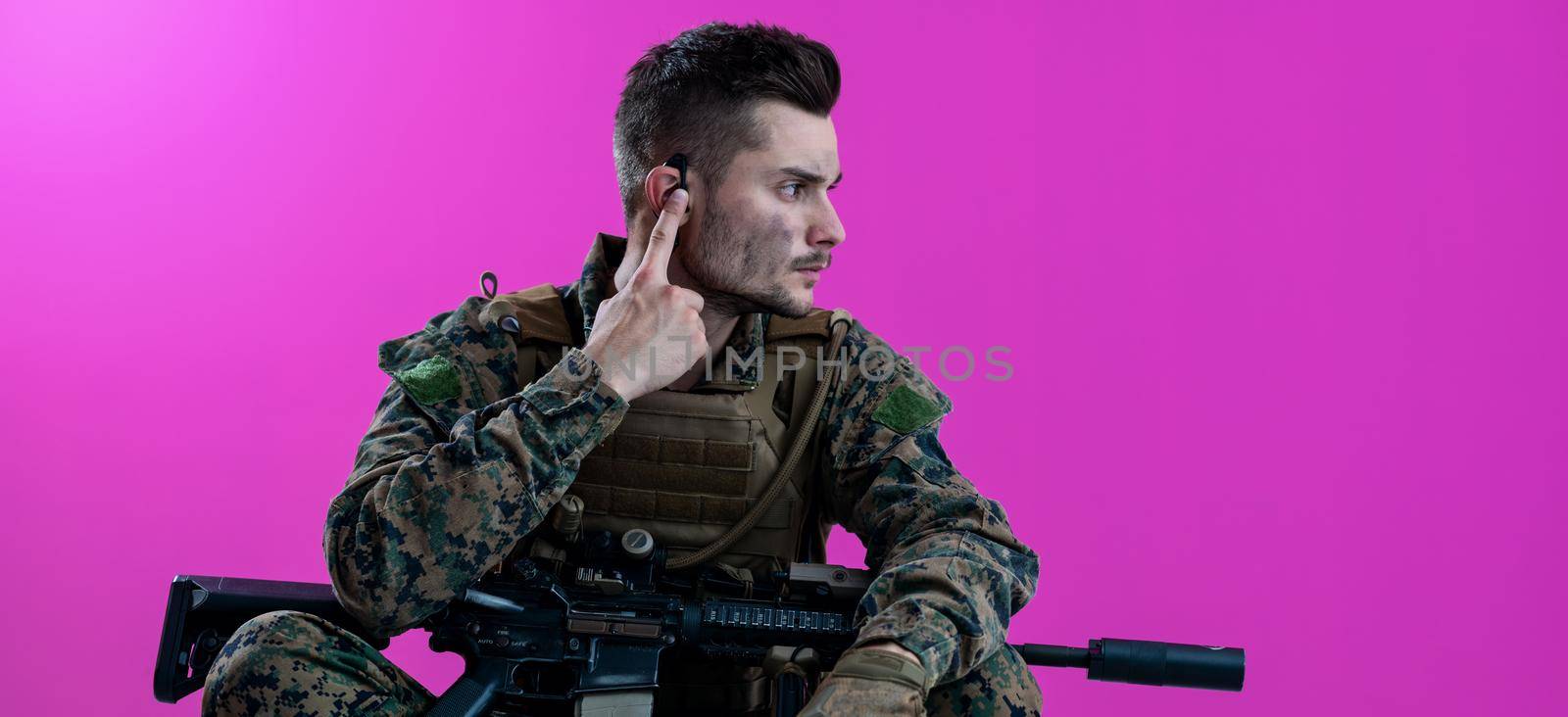 soldier preparing tactical and communication gear for action battle pink background