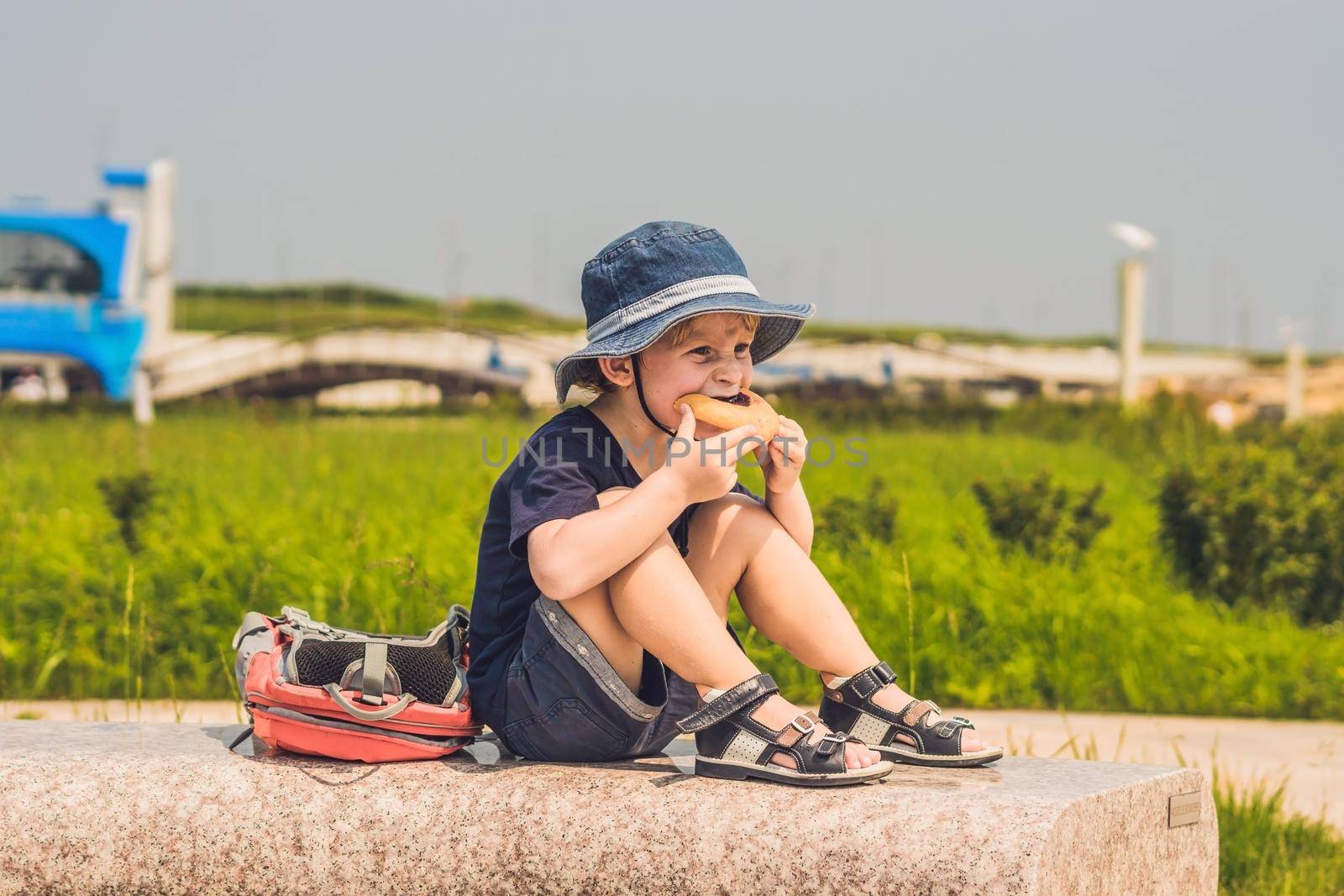 A boy eats his snack on a park bench by galitskaya