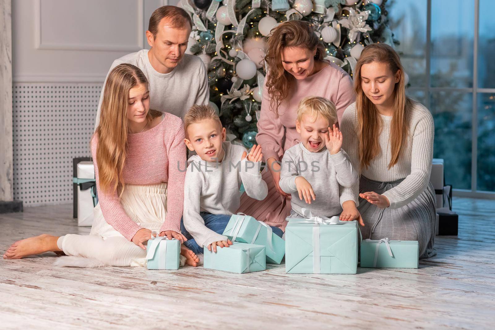 Big Happy family with many kids having fun and opening presents under the Christmas tree. Christmas family eve, christmas mood concept