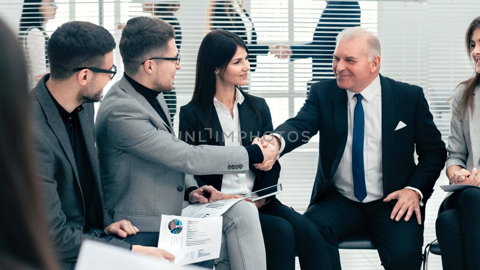 businessman and businesswoman shaking hands in a conference room by SmartPhotoLab