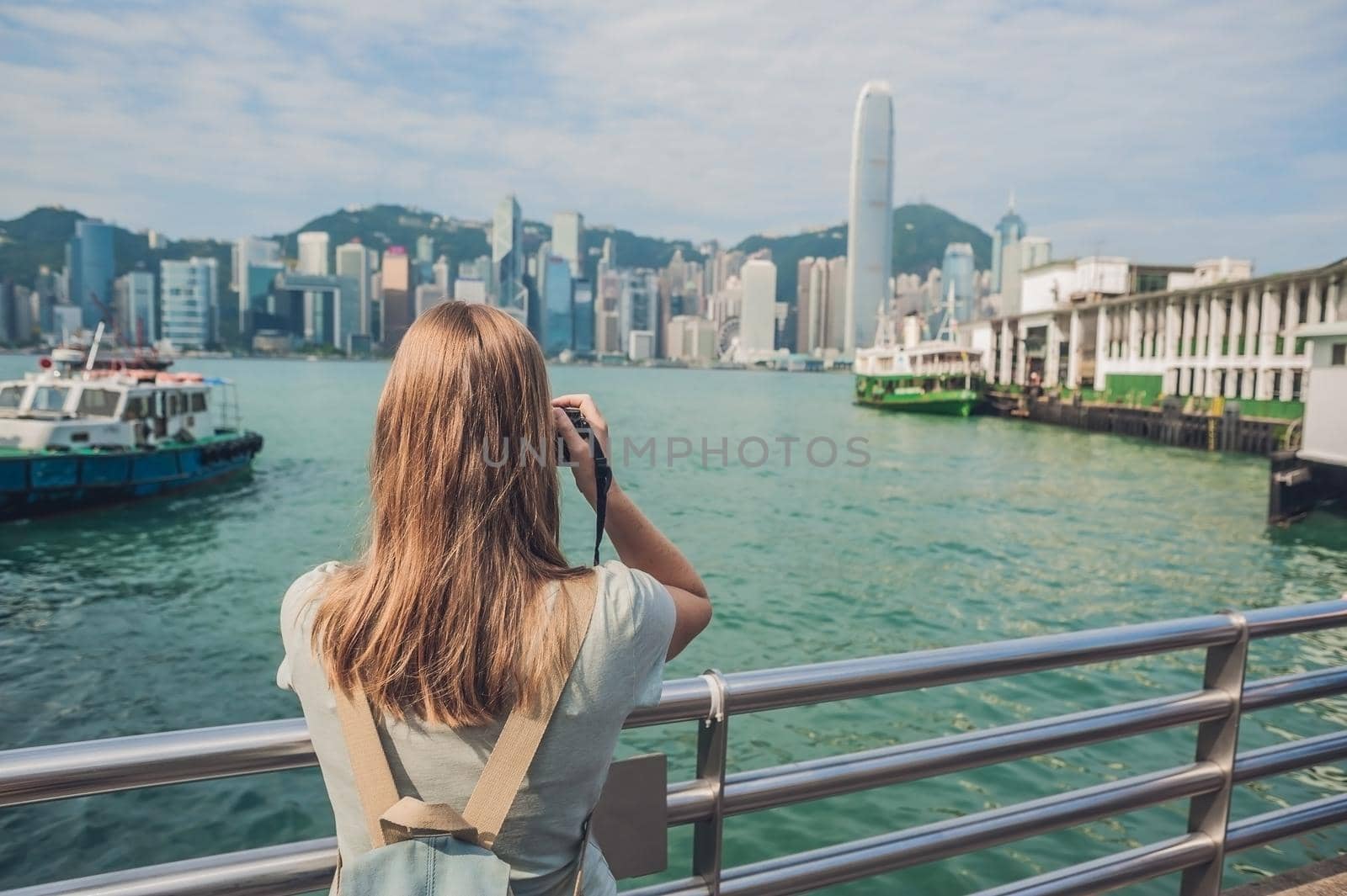 Young woman taking photos of victoria harbor in Hong Kong, China by galitskaya